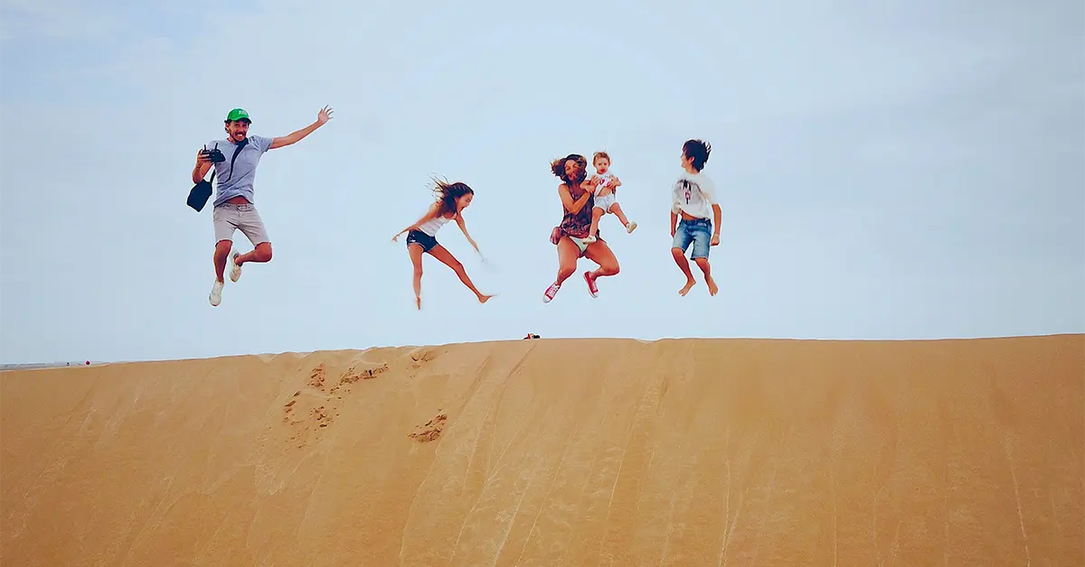 Family jumping on the dune during their private tour in Morocco