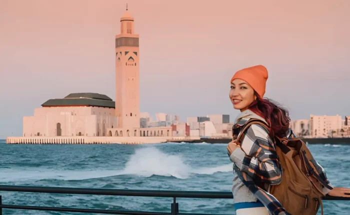 Viajero sonriente frente a la Mezquita Hassan II en Casablanca al inicio de un tour de 10 días de Casablanca al desierto del Sahara en Marruecos