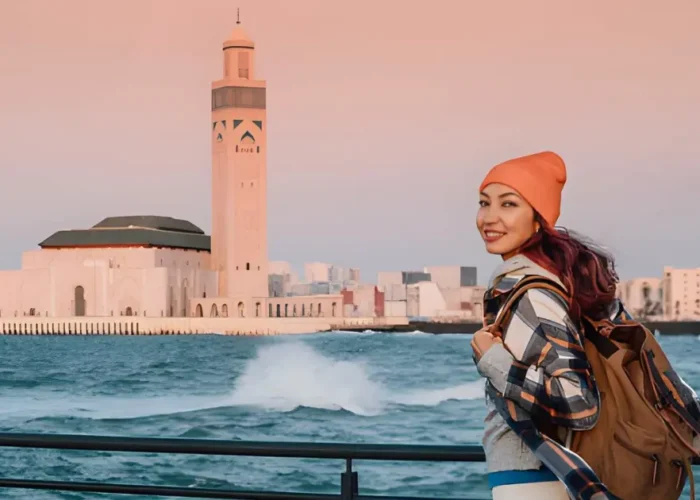 Smiling traveler in front of Hassan II Mosque in Casablanca at the start of a 10-day Casablanca to Sahara tour in Morocco