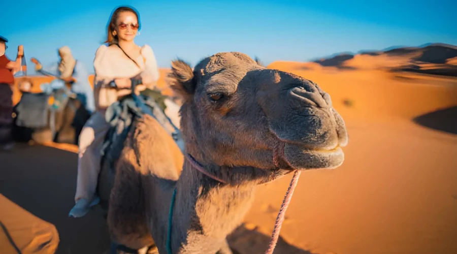 Smiling traveler riding a camel in the Sahara Desert during a 10-day Casablanca to Sahara tour in Morocco