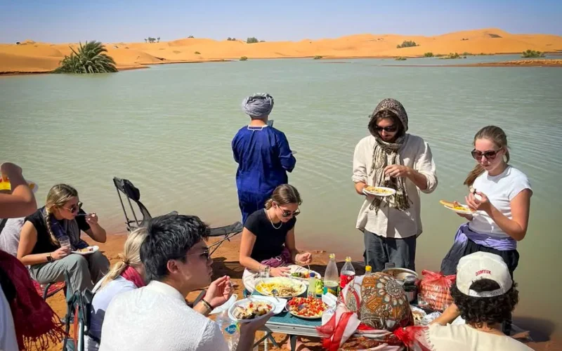 Group enjoying a traditional lunch by the lake in the Sahara Desert near Merzouga during a 14-day Morocco itinerary tour